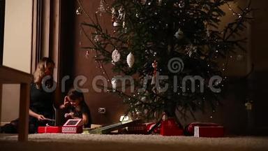 圣诞节前夕，我妈妈坐在圣诞树下，送给女儿一份礼物，<strong>还有</strong>一个女孩被捆起来
